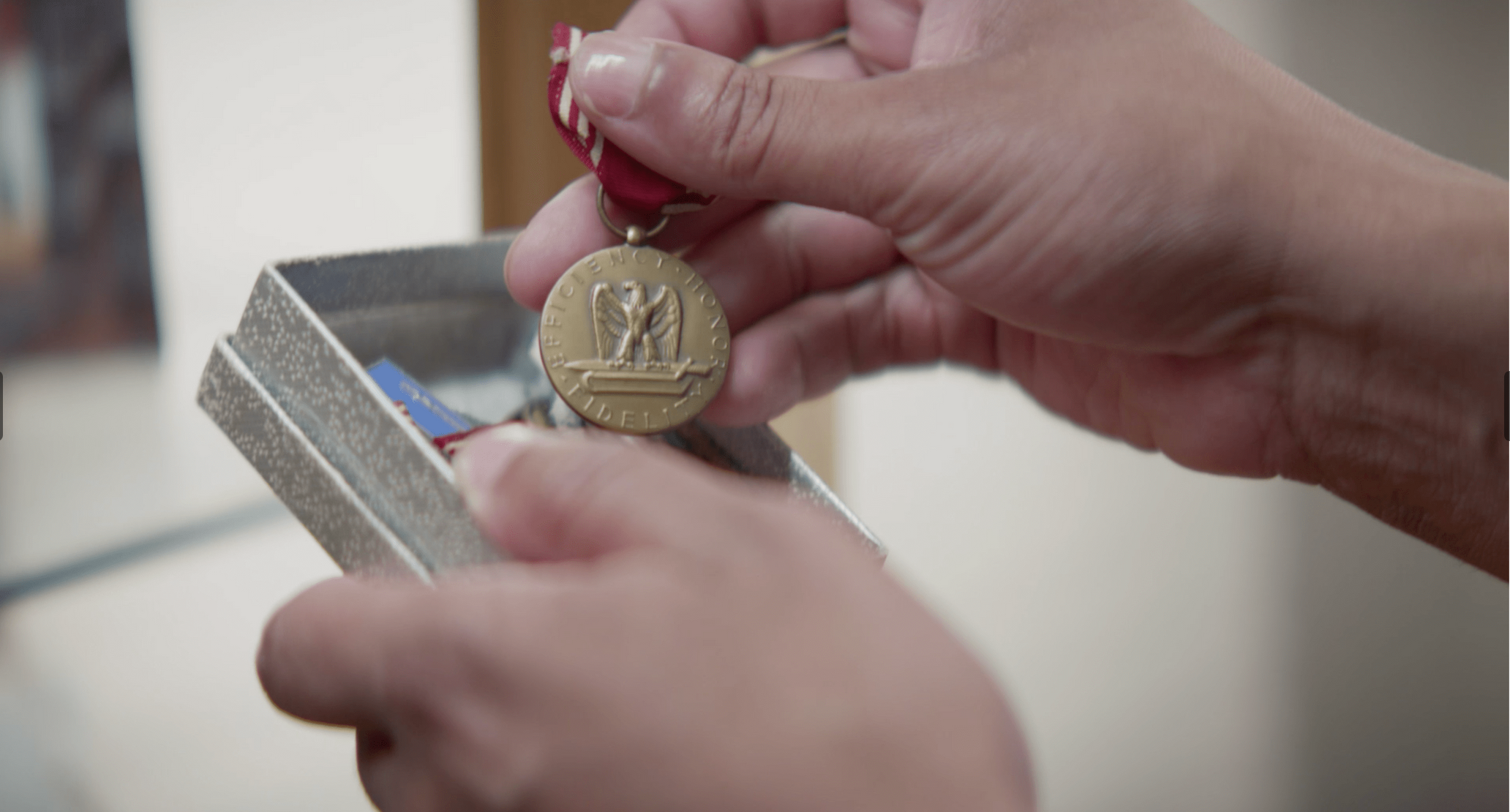 Hands holding a military medal in its presentation box, The Liberator