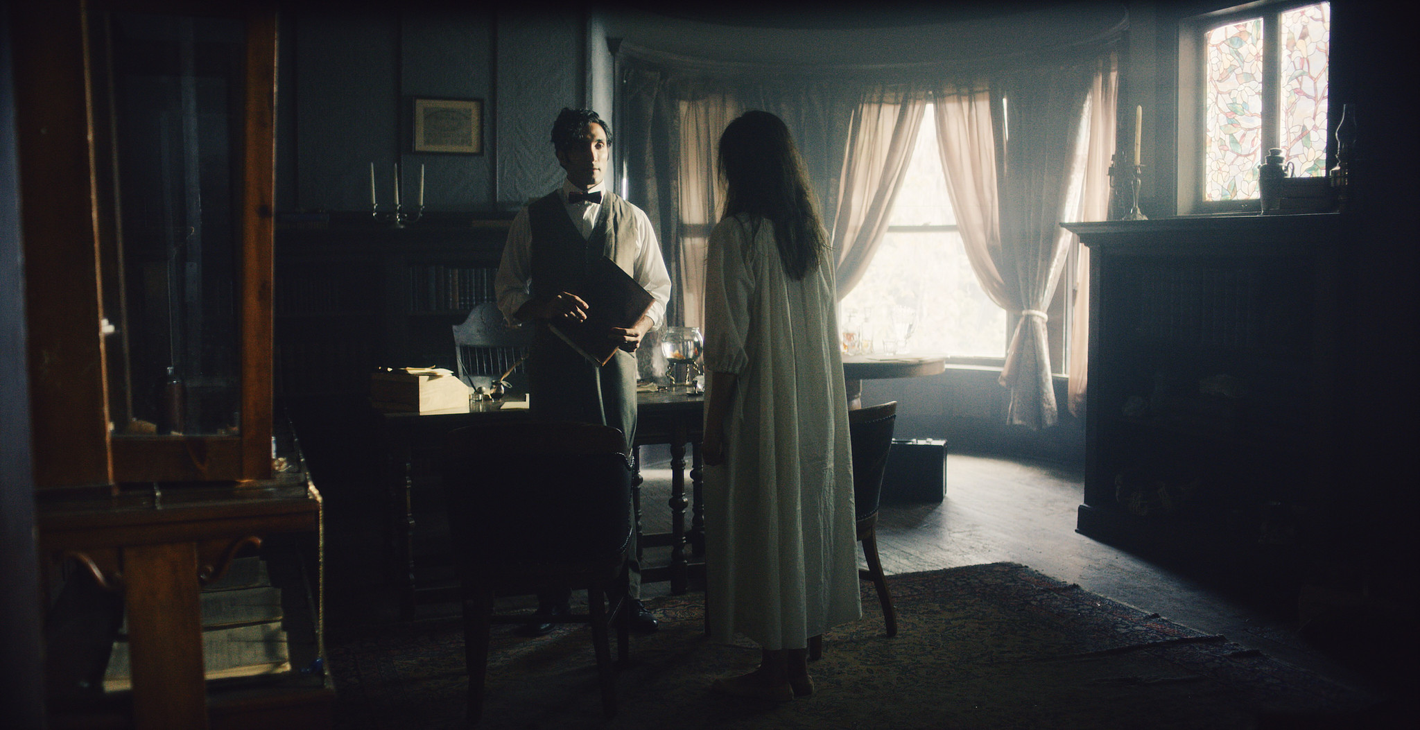 Patient in a white nightgown beside a curtained window in a dark period bedroom, The Mad Whale