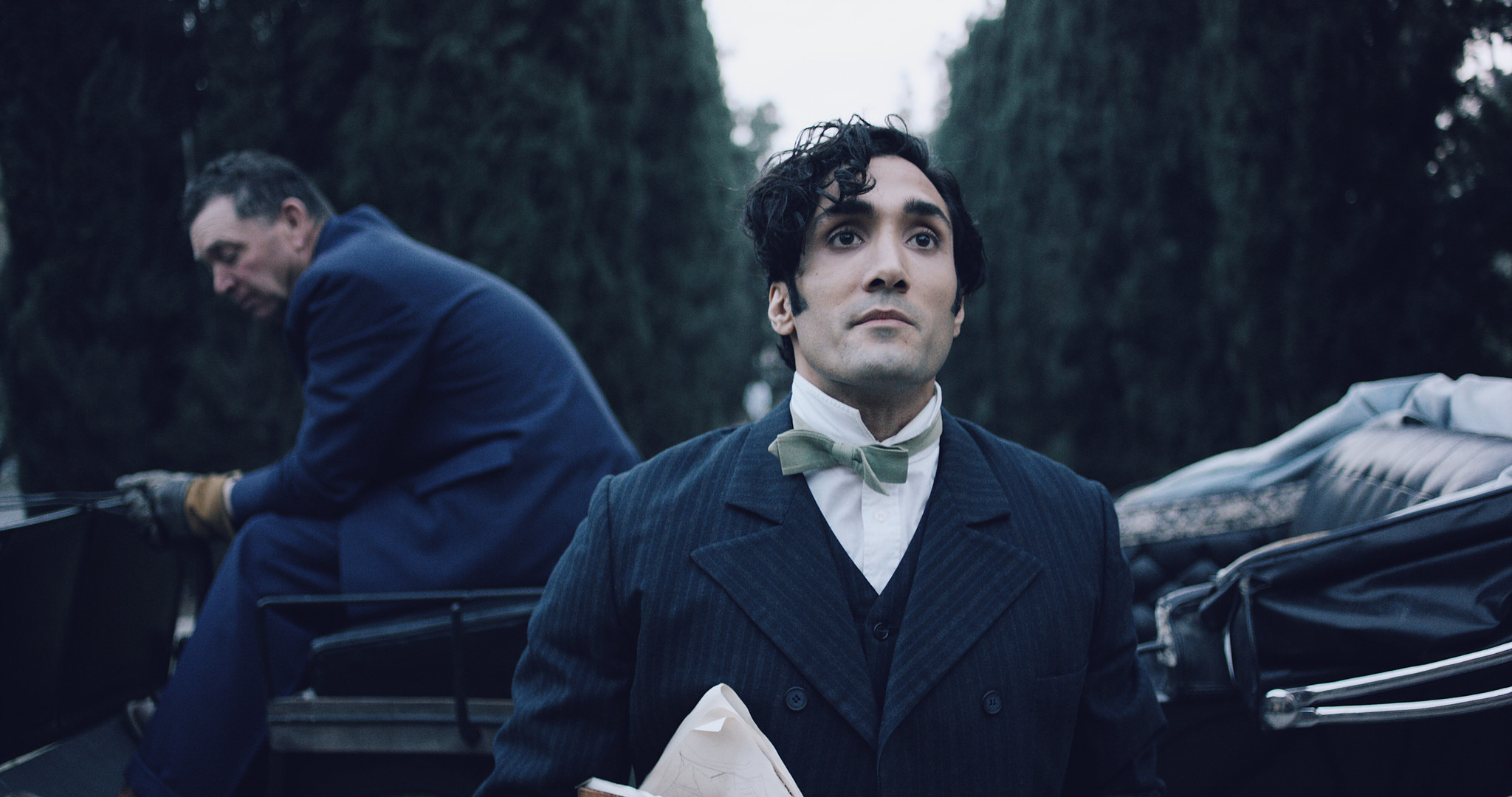 Two men in period suits in a tense exchange beside a bed in a dark room, The Mad Whale