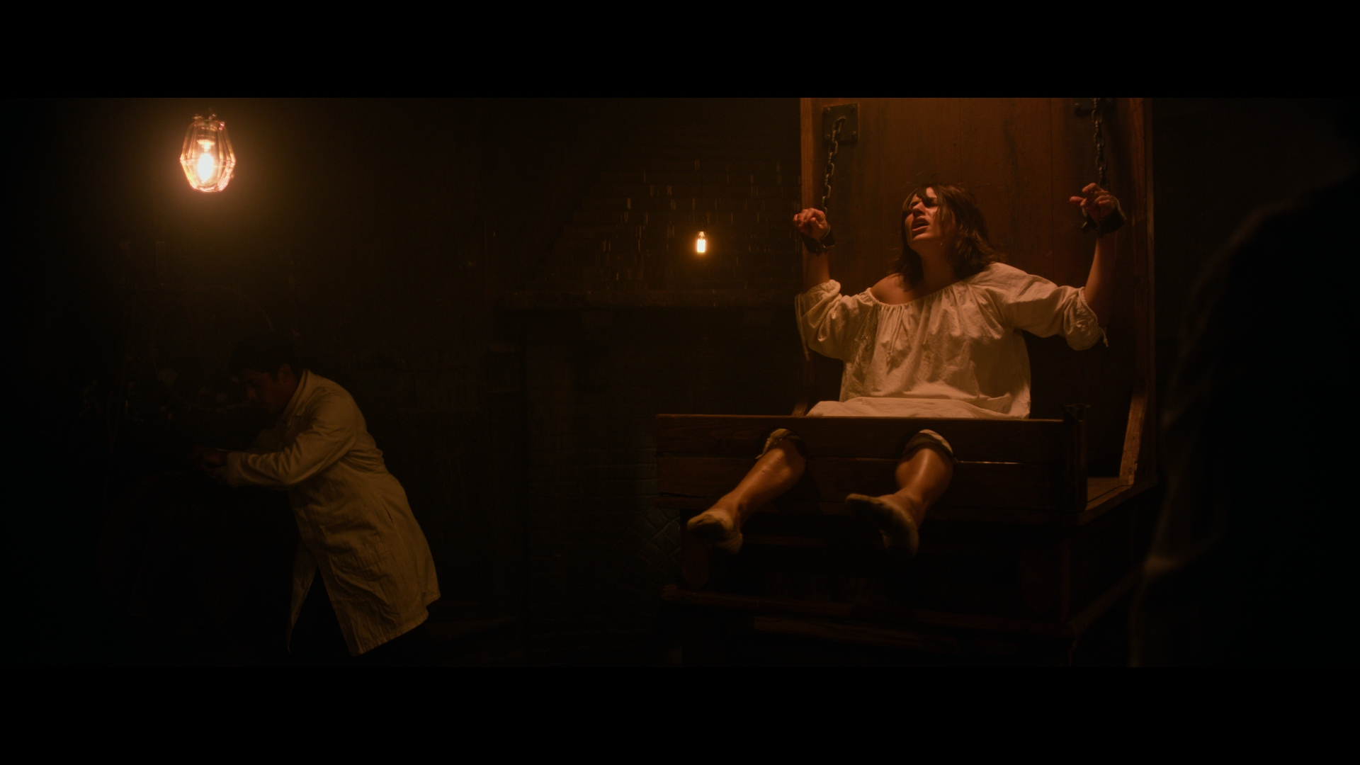 Restraint chair beneath a single hanging bulb in a dark asylum room, The Mad Whale